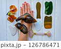 Two achatinas on hand and facial massage kit. Face roller and guasha massager made from natural stones and metal, flat lay. High quality photo Two achatinas on hand and facial massage kit. Face roller and guasha massager made from natural stones and metal, flat lay. High quality photo 126786471