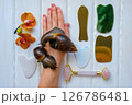Two achatinas on hand and facial massage kit. Face roller and guasha massager made from natural stones and metal, flat lay. High quality photo Two achatinas on hand and facial massage kit. Face roller and guasha massager made from natural stones and metal, flat lay. High quality photo 126786481