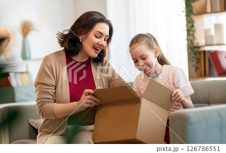 Mother and daughter are unpacking cardboard Mother and daughter are unpacking cardboard 126786551