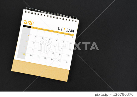 Top view of January 2026 desk calendar on black leather background. 126790370