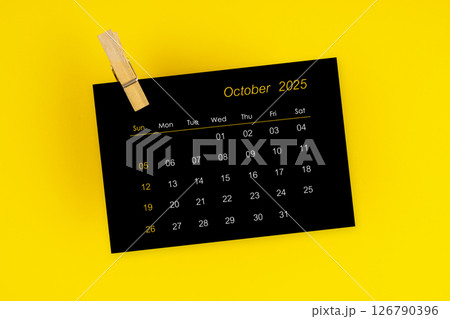 October 2025 black calendar with wooden clip on yellow background. October 2025 black calendar with wooden clip on yellow background. 126790396