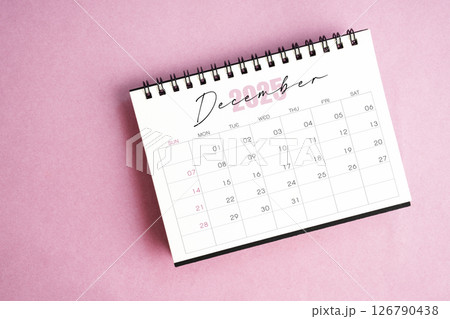 Top view of December 2025 desk calendar on pink background. 126790438