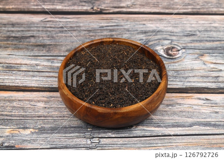 Dry black tea leaves isolated on wooden background, top view Dry black tea leaves isolated on wooden background, top view 126792726