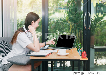 Young student with headphone watching lesson online and studying from home. She using laptop and learning online.  Distance learning online education. 126794408