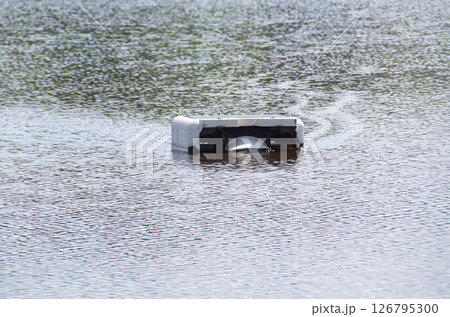 田植え前の水を張られた田んぼで水を掻き混ぜながら移動して雑草の成長を抑えるロボットが稼働している光景 126795300