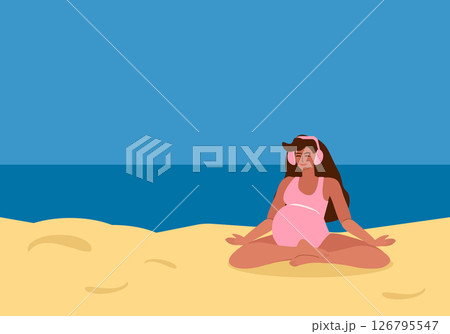 pregnant woman with headphones listening to music and meditating on beach pregnant woman with headphones listening to music and meditating on beach 126795547