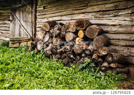 Firewood stacked near old barn in countryside with green grass Firewood stacked near old barn in countryside with green grass 126795828