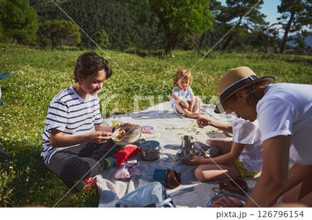Family Enjoying a Picnic Outdoors in a Scenic Mountain Landscape Family Enjoying a Picnic Outdoors in a Scenic Mountain Landscape 126796154