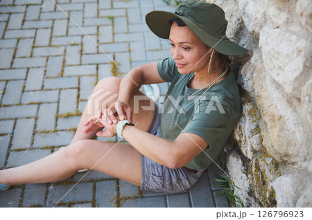 Woman Relaxing Outdoors Wearing Hat and Green Casual Outfit Woman Relaxing Outdoors Wearing Hat and Green Casual Outfit 126796923