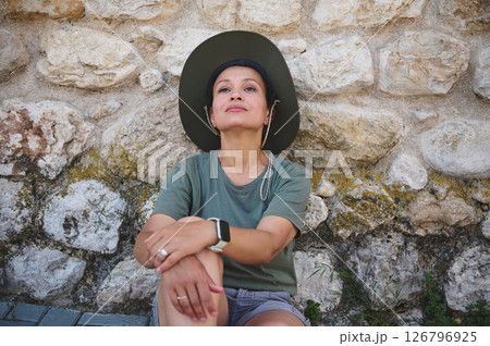 Woman Relaxing Outdoors Against Historic Stone Wall Background 126796925