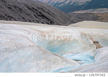 Crevasse in the ice from melting at Athabasca Glacier in Jasper National Park with cloudy sky 126797383