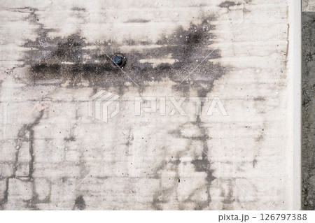 Directly above a white flat roof building drain  126797388