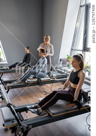 Woman training pilates on the reformer bed. Reformer pilates studio machine for fitness workouts in gym. Fit, healthy and strong authentical body. Fitness concept 126797406