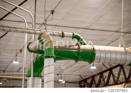Industrial HVAC metal Pipe header with multiple connections in a production facility with a coating of dust. 126797465