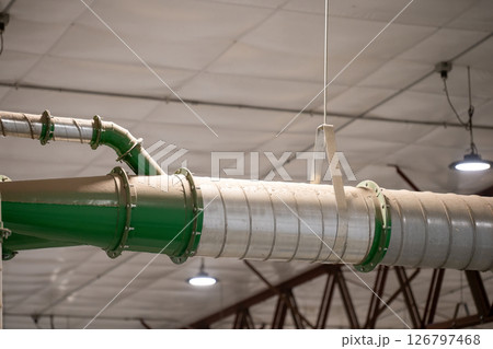 Industrial HVAC metal Pipe header with multiple connections in a production facility with a coating of dust. 126797468