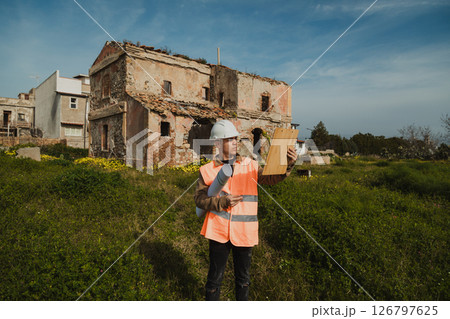 Engineer On The Construction Site Looking At The Old Building Engineer On The Construction Site Looking At The Old Building 126797625