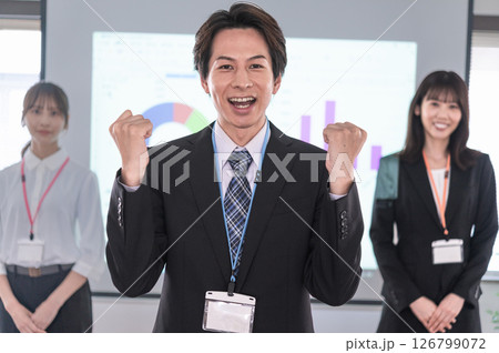 会議室のスクリーンの前でガッツポーズする男性 会議室のスクリーンの前でガッツポーズする男性 126799072