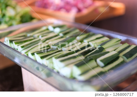 Close-up of sliced cucumbers on a white plate, served in a rustic wooden interior. Natural light enhances freshness. Shot Close-up of sliced cucumbers on a white plate, served in a rustic wooden interior. Natural light enhances freshness. Shot 126800717