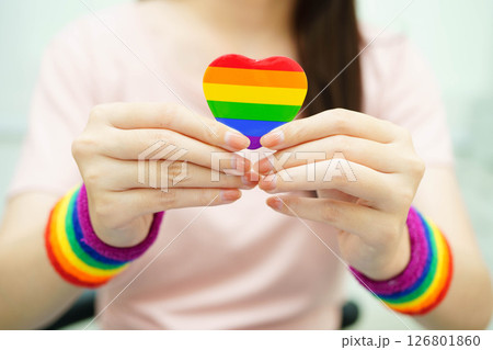 Asian woman holding LGBT heart with rainbow flag. Asian woman holding LGBT heart with rainbow flag. 126801860