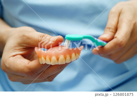 Asian senior woman patient clean teeth denture with toothbrush for chew food. 126801875