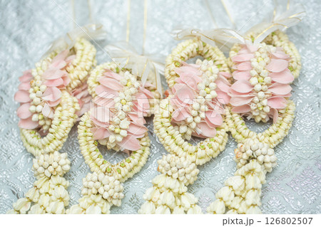 Beautiful Thai-style jasmine garland on a silver cloth background with an ancient Thai pattern. Beautiful Thai-style jasmine garland on a silver cloth background with an ancient Thai pattern. 126802507