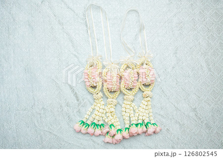 Beautiful Thai-style jasmine garland on a silver cloth background with an ancient Thai pattern. Beautiful Thai-style jasmine garland on a silver cloth background with an ancient Thai pattern. 126802545