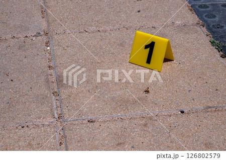 One yellow crime scene marker on the paving slab. High quality photo One yellow crime scene marker on the paving slab. High quality photo 126802579