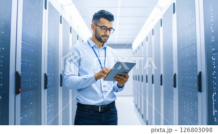 サーバールームでコンピューターをチェックする情報システム担当者 126803098