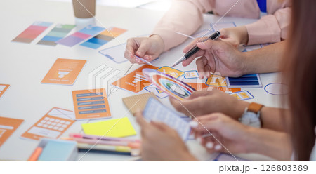 Team of Designers Collaborating. Professionals discussing layout concepts and color selections at a creative workspace. 126803389