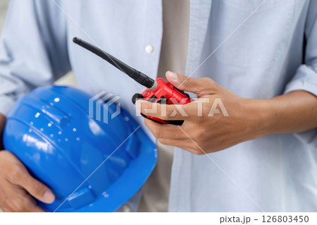 Safety and Communication in Construction. Close-up of engineer holding helmet and walkie-talkie. 126803450