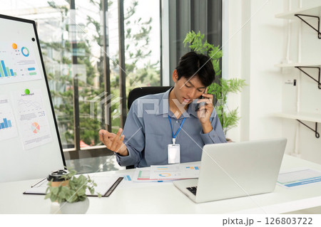 Professional Analyzing Financial Charts While on Phone Call in Office Professional Analyzing Financial Charts While on Phone Call in Office 126803722
