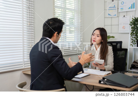 Financial Consultation. Engaging conversation between a financial advisor and client in a bright office. Financial Consultation. Engaging conversation between a financial advisor and client in a bright office. 126803744