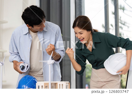 Sustainable Architecture Collaboration. Two architects celebrating project success in modern office. Sustainable Architecture Collaboration. Two architects celebrating project success in modern office. 126803747