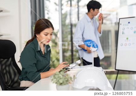 Focused Engineer Working on Tablet. A female engineer reviews project plans in a modern office. Focused Engineer Working on Tablet. A female engineer reviews project plans in a modern office. 126803755