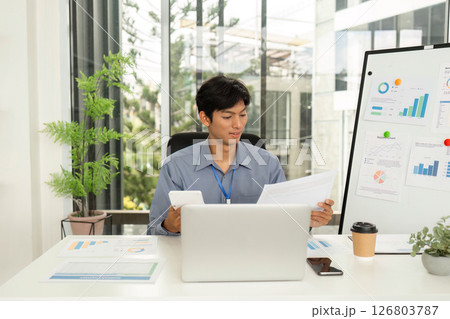Business Analysis and Reporting. Professional reviewing documents in modern office. 126803787