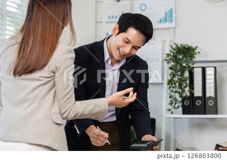 Collaborative Financial Discussion. Business partners engaging in financial calculations with a calculator. 126803800