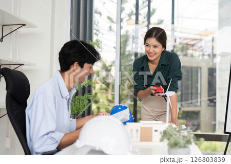 Innovative Collaboration. Professionals engaging in renewable energy discussions in a modern office setting. 126803839