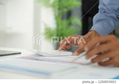 Efficient Data Entry. Professional using calculator while analyzing reports on a desk. Efficient Data Entry. Professional using calculator while analyzing reports on a desk. 126803881