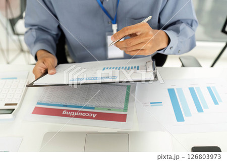 Financial Analysis and Reporting. Professional examining financial documents at desk. 126803973