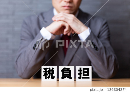 税負担のブロックとスーツを着て悩むミドル男性ビジネスマン 126804274