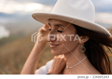 Hat Woman Outdoors: Early morning portrait of serene woman enjoying nature's beauty. 126805263