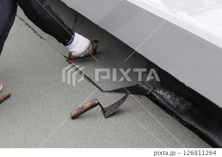 トーチバーナーで炙ったアスファルトシートを接着作業 126811264