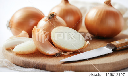 Fresh onions sliced on wooden cutting board with knife nearby, showcasing their layers and texture 126812107