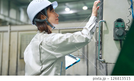 タブレットを持って工場機械を点検する女性作業員 126813515