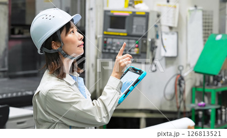 タブレットを持って工場機械を点検する女性作業員 126813521