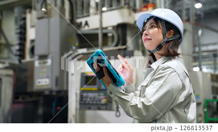 タブレットを持って工場機械を点検する女性作業員 126813537