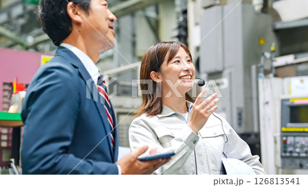 工場を視察する男性ビジネスパーソンと女性作業員 126813541