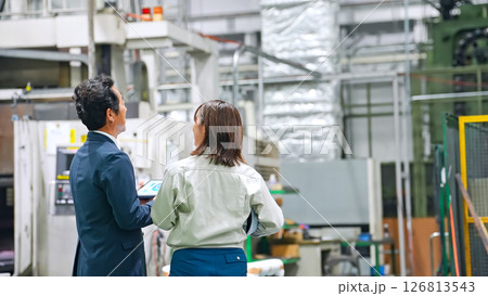 工場を視察する男性ビジネスパーソンと女性作業員 工場を視察する男性ビジネスパーソンと女性作業員 126813543