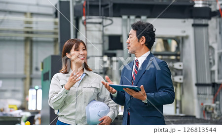 工場を視察する男性ビジネスパーソンと女性作業員 126813544