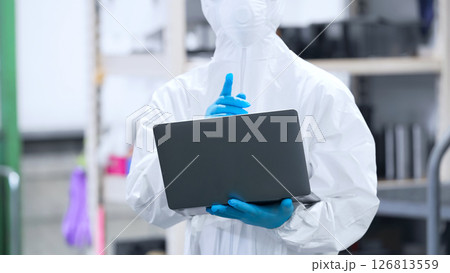 工場でノートPCを使う防護服を着た作業員 126813559